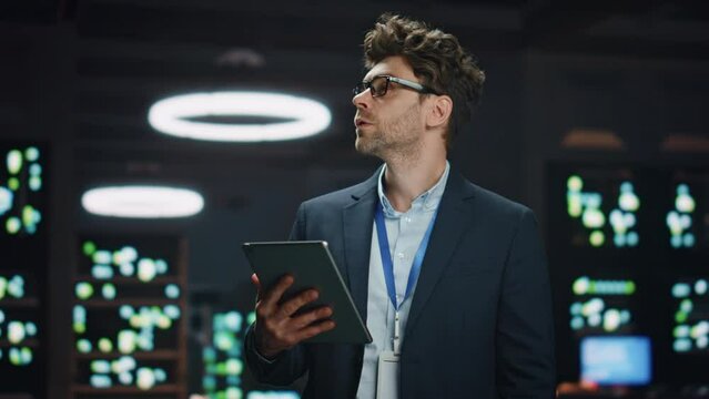 Serious IT specialist working tablet in data center closeup. Man looking asides
