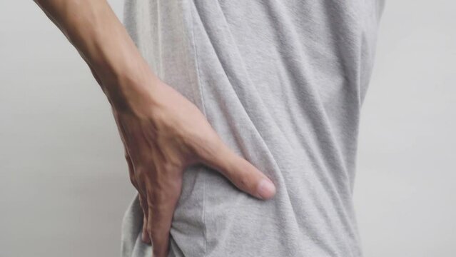 Asian man suffering from right sided back pain. This can be caused by mechanical or pathological processes.