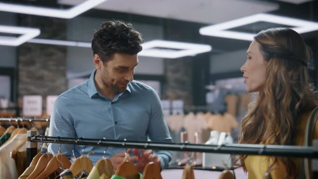 Lady shopaholic choosing clothes at boutique closeup. Assistant talking client