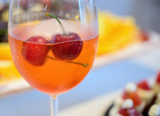 Ice cold fresh cocktail drinks with cherries. Glass covered with water drops condensation. Out-of-focus dessert background.