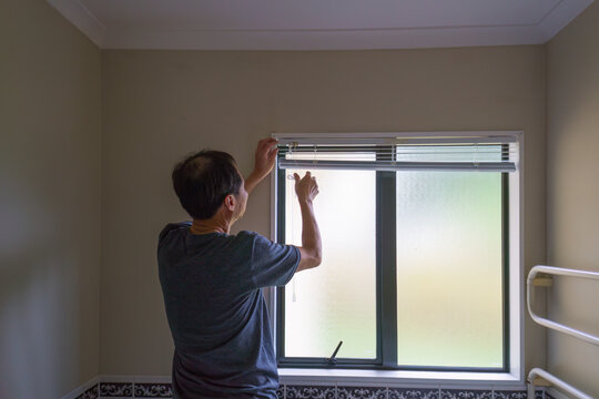Man installing bathroom blinds. Home renovation project.