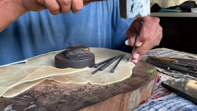 Indonesian elderly man making carving hand made wayang shadow puppet