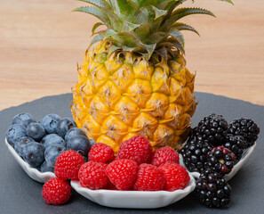 Ananas Frucht mit Himbeeren, Brombeeren und Heidelbeeren auf einer Schiefertafel - 702049013
