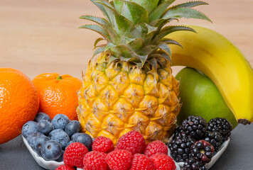 Ananas Frucht mit Himbeeren, Brombeeren, Heidelbeeren, Mandarine, Banane, Apfel, auf einer Schiefertafel - 702049053