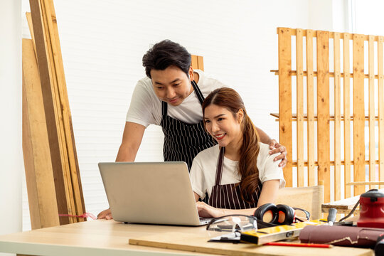 Young couple brainstorming creative interior design ideas for their new cafe business start-up on a laptop, choosing flexible workspace layout to drive customer engagement