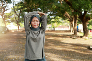 athletic young asian muslim girl in sportswear standing, stretching before workout with copyspace