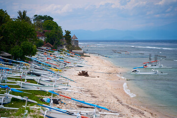 Traditional local colored fisherman's catamaran boats are lined up on the ocean shore on an island...
