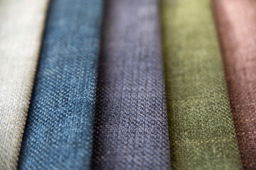 A selection of assorted pieces of furniture fabric samples in blue, purple and green colors for upholstery of sofas and armchairs. Matting fabric of different shades in the form of stripes close-up.
