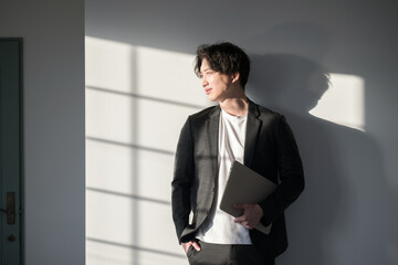 Silhouette of a handsome businessman holding a laptop Image of a cool guy who worries, thinks, changes jobs, etc.