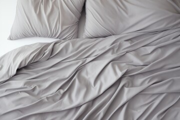 Crumpled gray bed linen with pillows and blankets on the bed