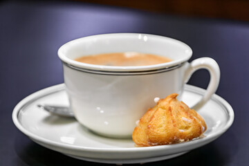 Traditional French macaron cookie and a cup of latte, coffee with milk served at breakfast at an artisanal bakery in Strasbourg, Alsace, France