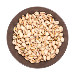 Pistachios in their shells, roasted and salted, in a brown bowl. Crunchy roasted fruits of Pistacia vera, with opened shells and seeds within. Close-up, from above, isolated over white, food photo.