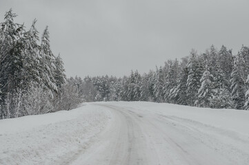 Obraz premium a road in a snowy winter forest after a snowfall