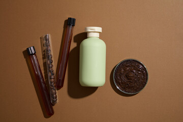 Minimal concept for advertising organic product for skin and body care. On a brown background, a green bottle displayed with coffee ingredient on test tubes and petri dish. Top view, space for design