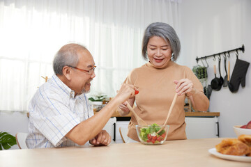 senior couple enjoy cooking and eating salad in the kitchen
