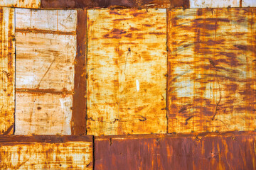 rusty steel sheets welded together wall patchwork with leftovers of faded white paint, closeup full-frame background and texture.