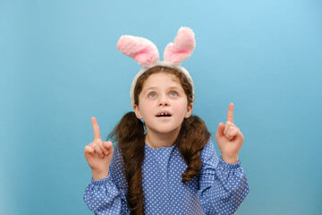 Portrait of amazed beautiful little girl kid wearing pink fluffy easter bunny ears, surprised...
