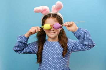 Portrait of playful funny smiling little girl kid wearing fluffy easter bunny ears, holding near...