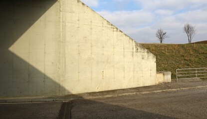 Exit of a road underpass made of reinforced concrete  with grass, bare trees and cloudy sky on the...