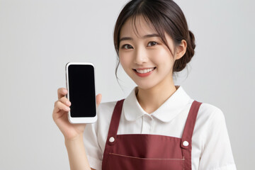 Fototapeta premium スマートフォンを操作しながら微笑むエプロンを着た美人主婦