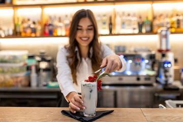 Barmaid preparing cocktails in a bar for her clients - Bartender at work in a club, beautiful young...