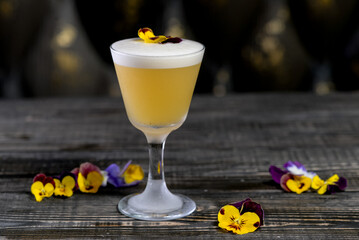 alcoholic cocktail of yellow color decorated with flowers on the board