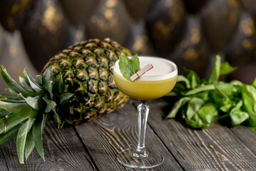 green cocktail on a wooden board with basil leaves and pineapple