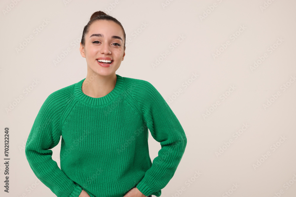 Wall mural Beautiful young woman in stylish warm sweater on light grey background, space for text