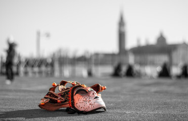 an old traditional Venetian mask left on the ground by tourists