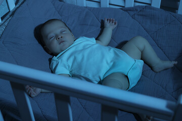 Cute newborn baby sleeping in crib at night
