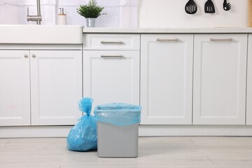 Plastic garbage bag and trash can in kitchen, space for text