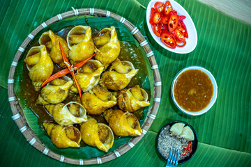 Steamed Spotted Babylon Blanching (Fresh Sea Babylonia Areolata Shell Boiled) served with passion fruit sauce goodtasty decorated with spices side view