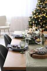 Christmas table setting with festive decor and dishware in room