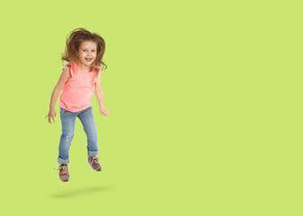 Cute girl jumping on light green background, space for text