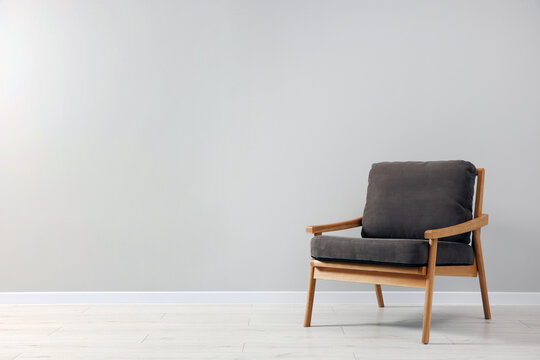 Comfortable armchair near light grey wall indoors. Space for text