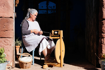 Concentrated senior female making thread with an old thread maker spinning machine
