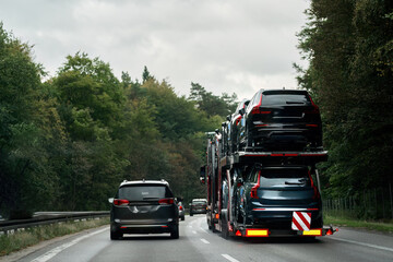 A car transporter truck with a hydraulic trailer loaded with new cars to the happy customers. The...