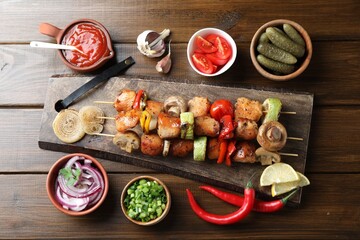 Delicious shish kebabs, mushroom, tomato and zucchini served on wooden table, flat lay