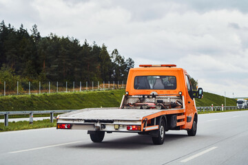 A Car Carrier Tow Truck Driving Fast on the Road with No Vehicle Loaded. A Modern and New Tow Truck...