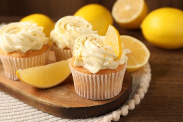 Tasty cupcakes with cream, zest and lemons on wooden table, closeup