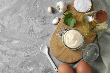 Tasty mayonnaise in jar and ingredients on gray textured table, flat lay. Space for text