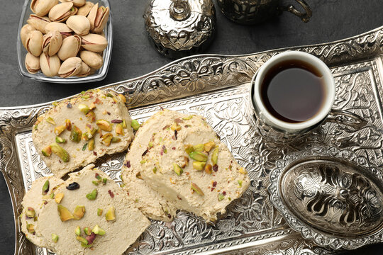 Tasty halva with pistachios served on grey table, flat lay