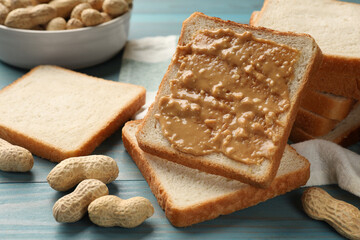 Delicious toasts with peanut butter and nuts on light blue wooden table, closeup