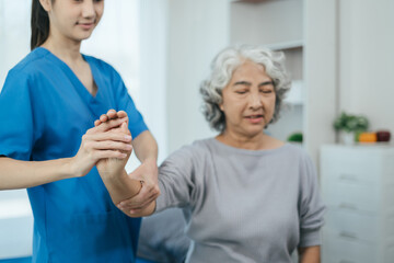senior woman doing exercise at clinic with physiotherapist. help of a personal trainer during a...