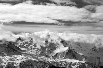 Black and white snow mountains in sunlight clouds
