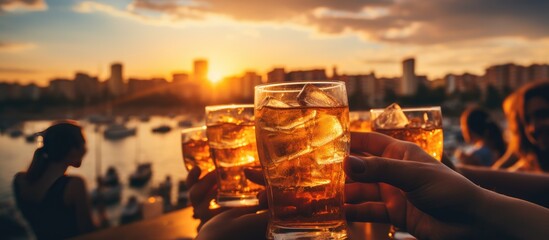 Group of people's hands toasting with a glass of drink at sunset. Close up shot. - obrazy, fototapety, plakaty
