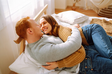 Young couple resting in bed at home. A couple in love spends time together on the bed, hugs each...