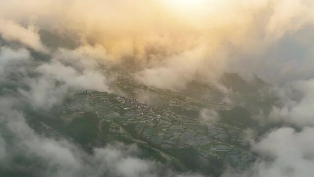 Aerial view, sea of mist in the mountains, forest in the morning of Nepal Van Java with colorful villages on the slopes of a volcano. Hillside countryside, Magelang, Indonesia
