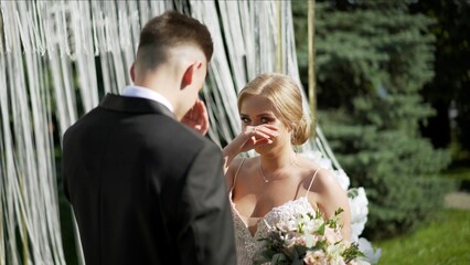 The bride wipes tears from her eyes. The bride and groom at the exit registration. A bride wipes a...
