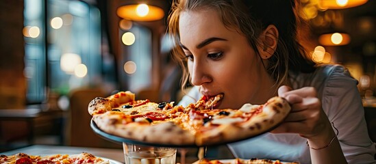 child girl eating pizza with appetite in pizzeria eat tasty not healthy food. with copy space image. Place for adding text or design - obrazy, fototapety, plakaty